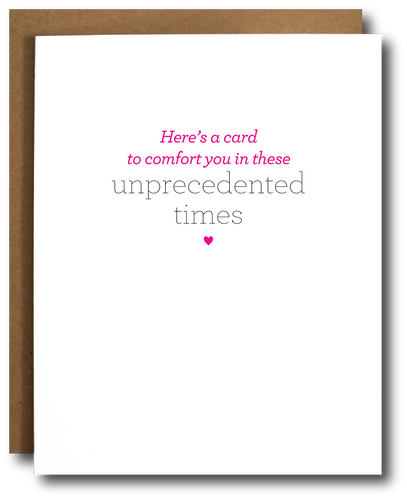 Minimalist greeting card with the message 'Here’s a card to comfort you in these unprecedented times' in pink and gray text, centered on a white background with a small pink heart below. Brown kraft paper envelope partially visible behind the card.