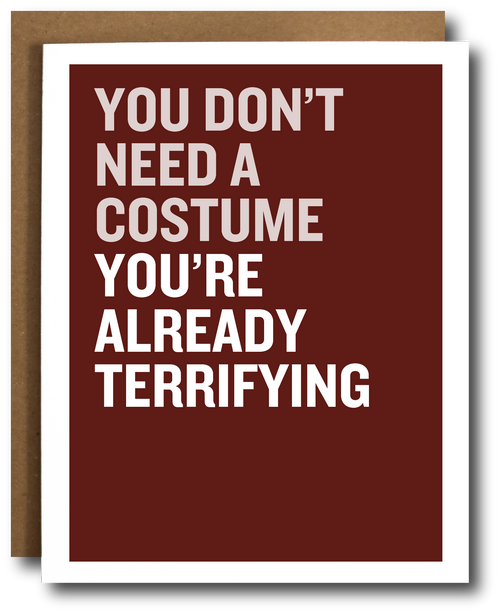 A greeting card with a dark red background and bold white text reading 'YOU DON'T NEED A COSTUME YOU'RE ALREADY TERRIFYING', shown with a brown kraft envelope behind it on a white background.