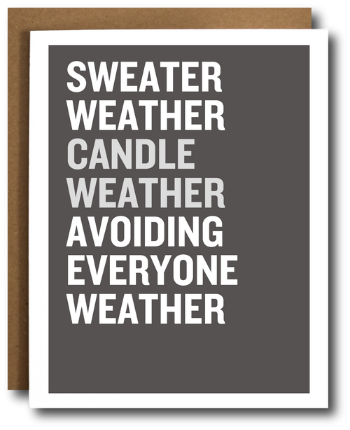 A greeting card with a dark gray face and bold white text reading 'SWEATER WEATHER CANDLE WEATHER AVOIDING EVERYONE WEATHER,' shown with a brown kraft envelope behind it on a white background.