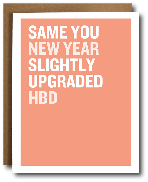 Greeting card with text 'SAME YOU NEW YEAR SLIGHTLY UPGRADED HBD' on a peach background with a brown envelope.