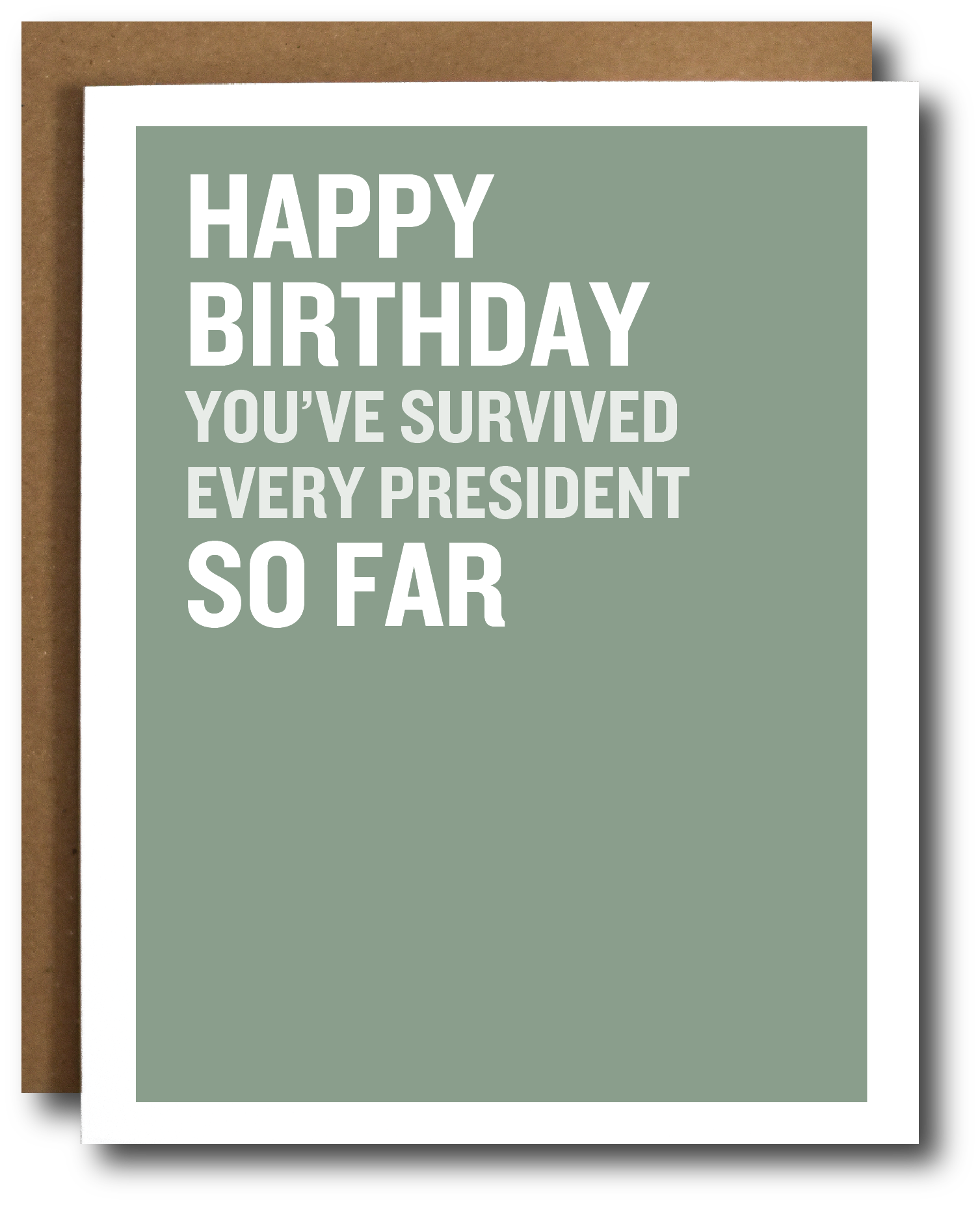 A birthday card with a sage green background and bold white text reading 'HAPPY BIRTHDAY YOU'VE SURVIVED EVERY PRESIDENT SO FAR,' shown with a brown envelope behind it on a white background.