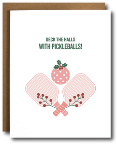 A holiday greeting card with a depiction of pickleball paddles and a stylized Christmas tree, with the text 'DECK THE HALLS WITH PICKLEBALLS!' on the front.