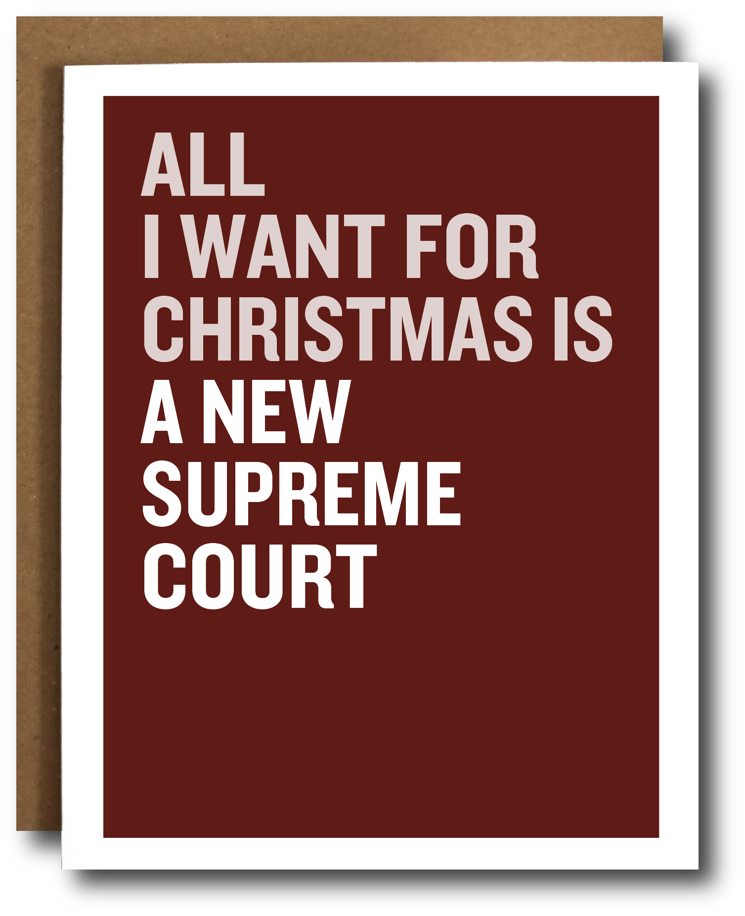 A greeting card with a dark red background and bold white text reading 'ALL I WANT FOR CHRISTMAS IS A NEW SUPREME COURT,' shown with a brown envelope behind it on a white background.
