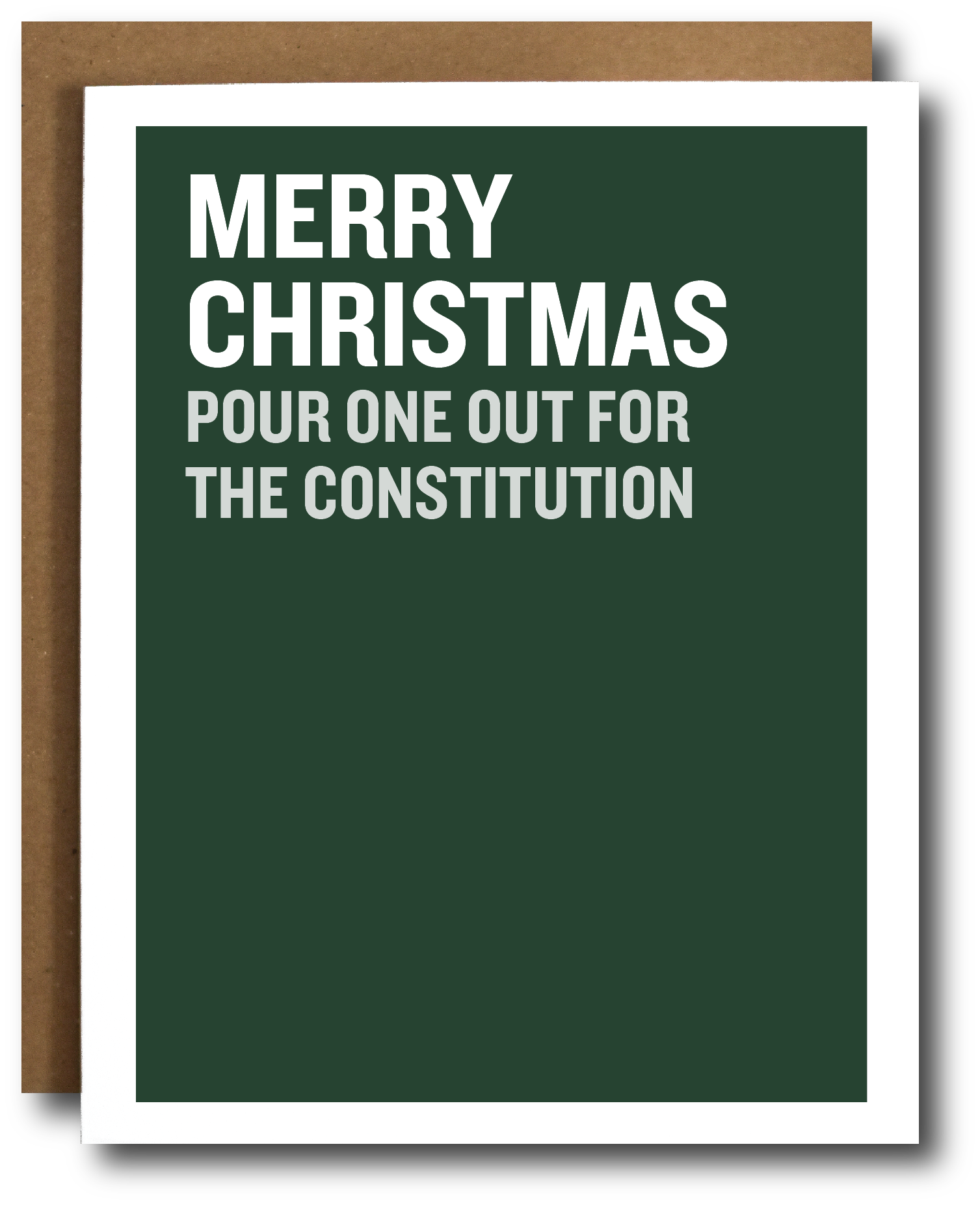A dark green Christmas greeting card with bold white text reading 'MERRY CHRISTMAS POUR ONE OUT FOR THE CONSTITUTION', shown with a brown kraft envelope behind it on a white background.