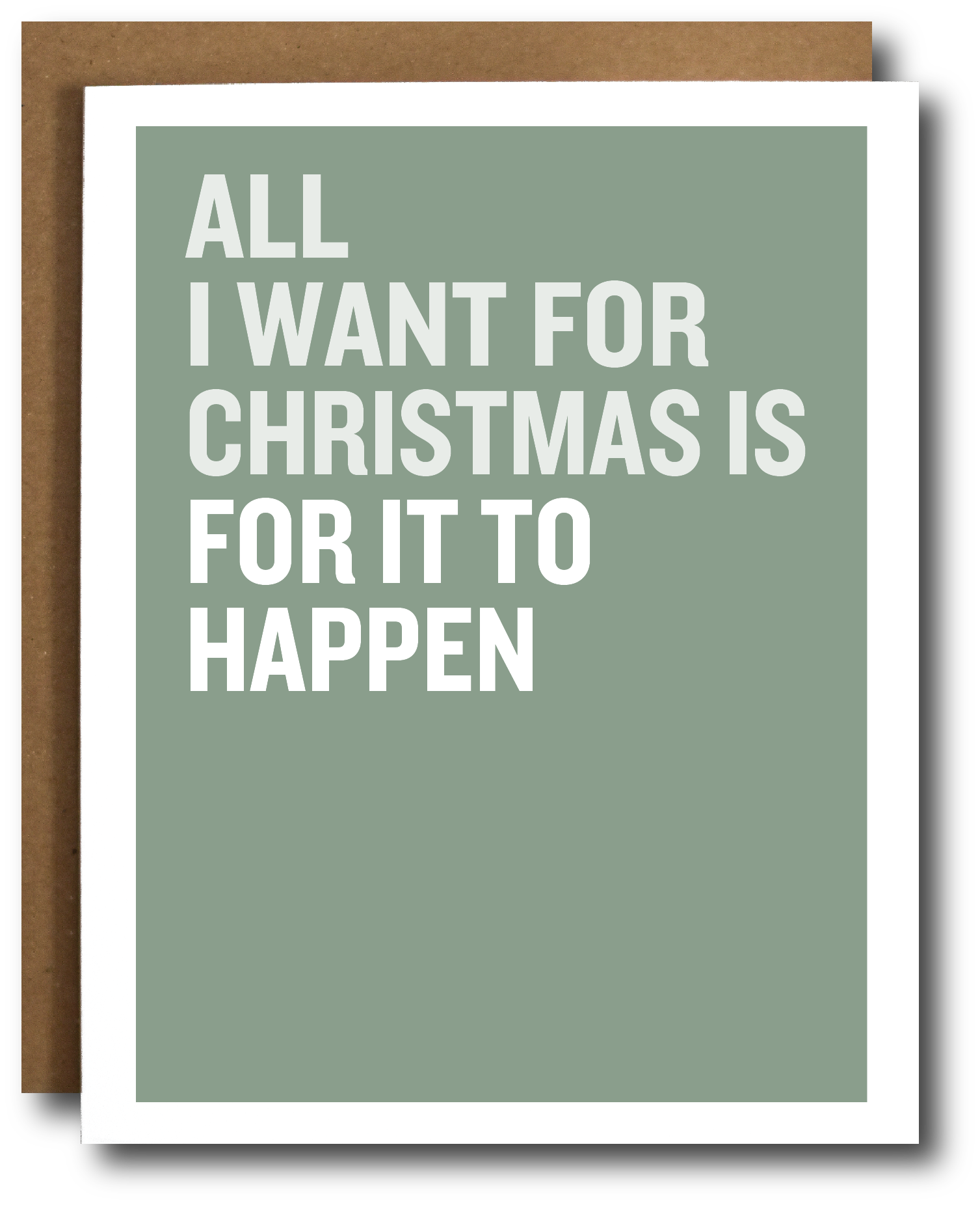 A greeting card with a sage green background and bold white text reading 'ALL I WANT FOR CHRISTMAS IS FOR IT TO HAPPEN,' shown with a brown kraft envelope behind it on a white background.