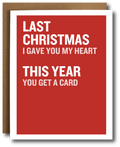 A red greeting card with white text reading 'LAST CHRISTMAS I GAVE YOU MY HEART THIS YEAR YOU GET A CARD', shown with a brown envelope behind it on a white background.