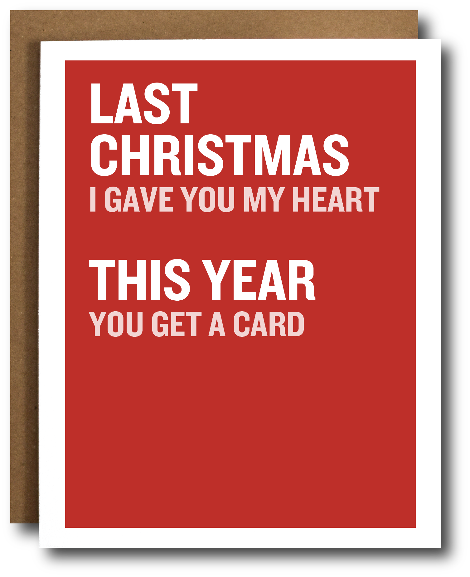 A red greeting card with white text reading 'LAST CHRISTMAS I GAVE YOU MY HEART THIS YEAR YOU GET A CARD', shown with a brown envelope behind it on a white background.