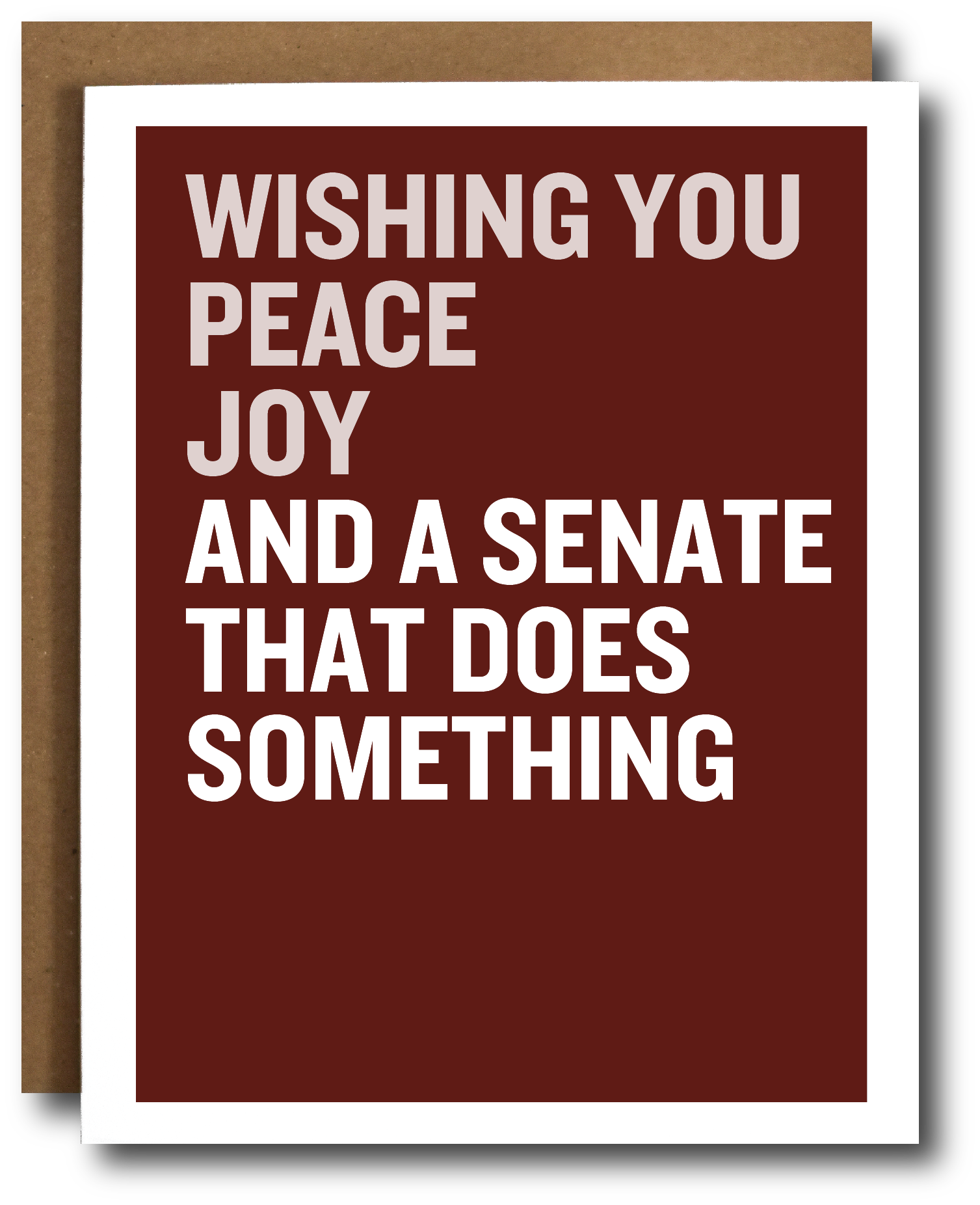 A greeting card with a dark red-brown background and bold white text reading 'WISHING YOU PEACE JOY AND A SENATE THAT DOES SOMETHING,' shown with a brown envelope behind it on a white background.