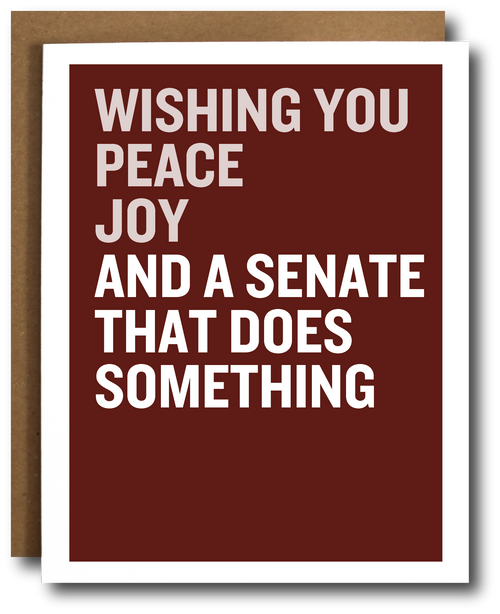 A greeting card with a dark red-brown background and bold white text reading 'WISHING YOU PEACE JOY AND A SENATE THAT DOES SOMETHING,' shown with a brown envelope behind it on a white background.