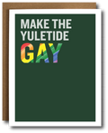 A greeting card with a dark green background and the text 'MAKE THE YULETIDE GAY' in white and rainbow-striped letters, shown with a brown kraft envelope behind it on a white background.