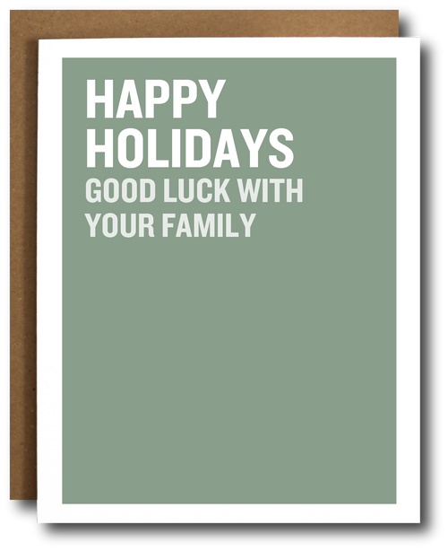 A holiday greeting card with a sage green background and bold white text reading 'HAPPY HOLIDAYS GOOD LUCK WITH YOUR FAMILY,' shown with a brown envelope behind it on a white background.