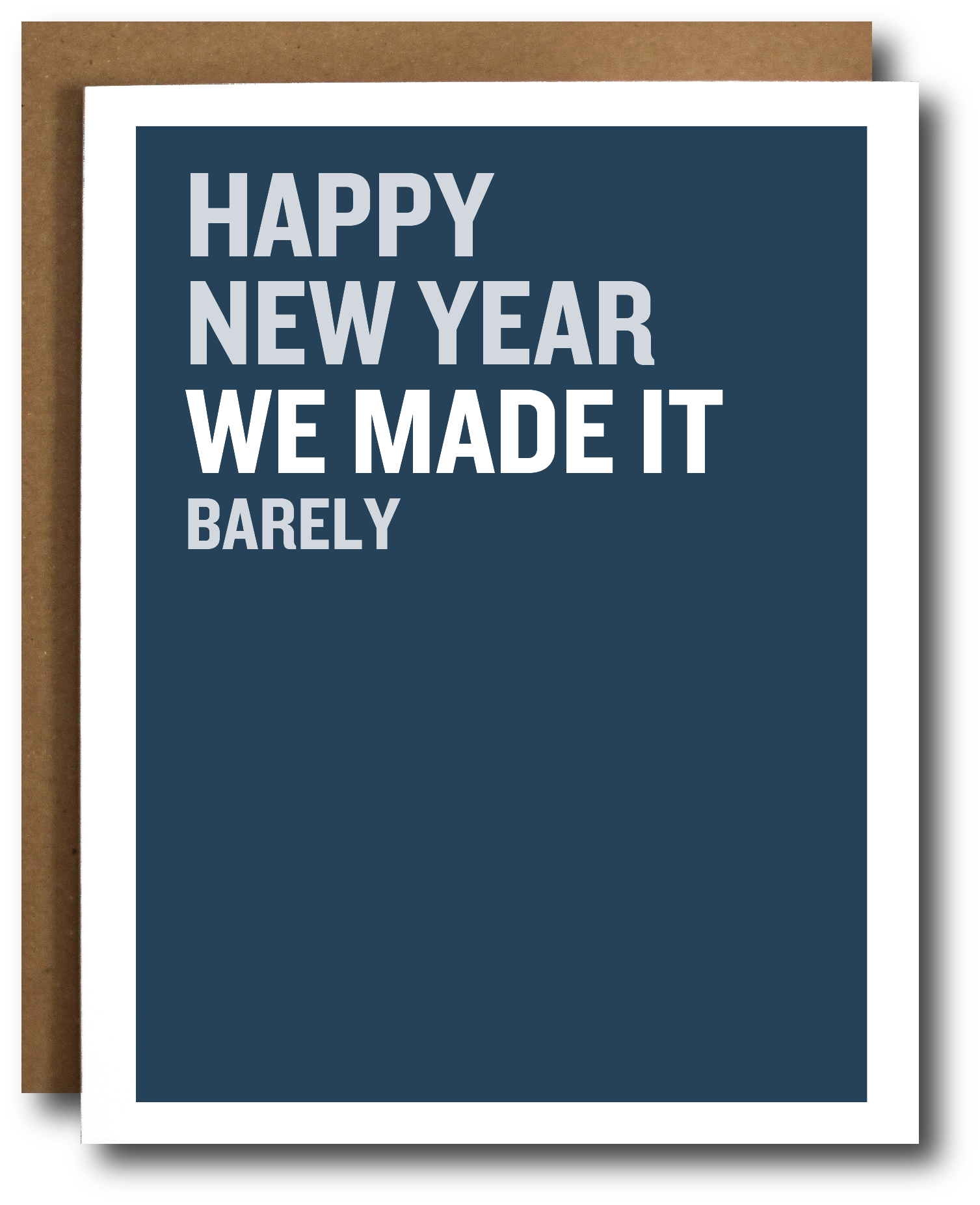A greeting card with a dark blue front and white border, shown with a brown envelope behind it. The card reads, 'HAPPY NEW YEAR WE MADE IT BARELY' in white uppercase text.