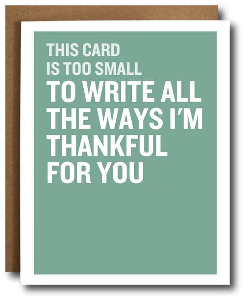 A greeting card with a sage green background and bold white text reading, 'THIS CARD IS TOO SMALL TO WRITE ALL THE WAYS I’M THANKFUL FOR YOU,' shown with a brown kraft envelope behind it on a white background.