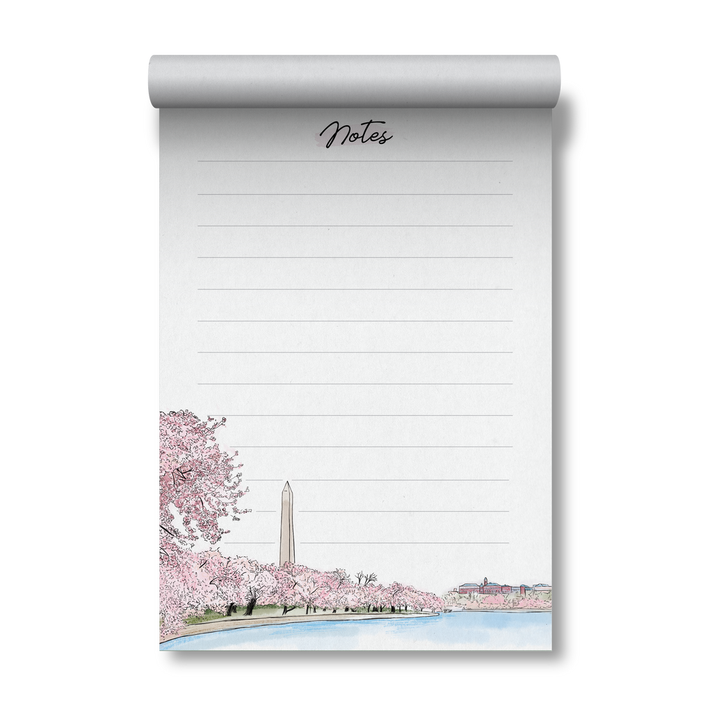 A lined notepad with a rolled top edge, featuring a hand-drawn illustration of cherry blossom trees, the Washington Monument, and a waterfront scene. The word 'Notes' appears at the top in cursive.