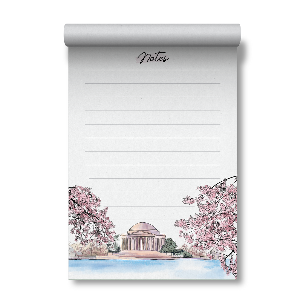 A lined notepad with a rolled top edge, featuring a hand-drawn illustration of cherry blossom trees, the Jefferson memorial, and a waterfront scene. The word 'Notes' appears at the top in cursive.